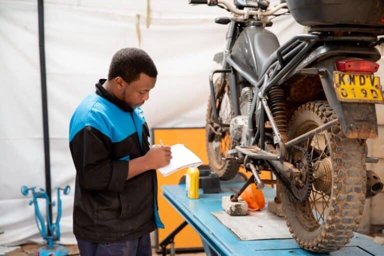 Mechanic tuning a Kibo motorcycle in a well-organized service center.